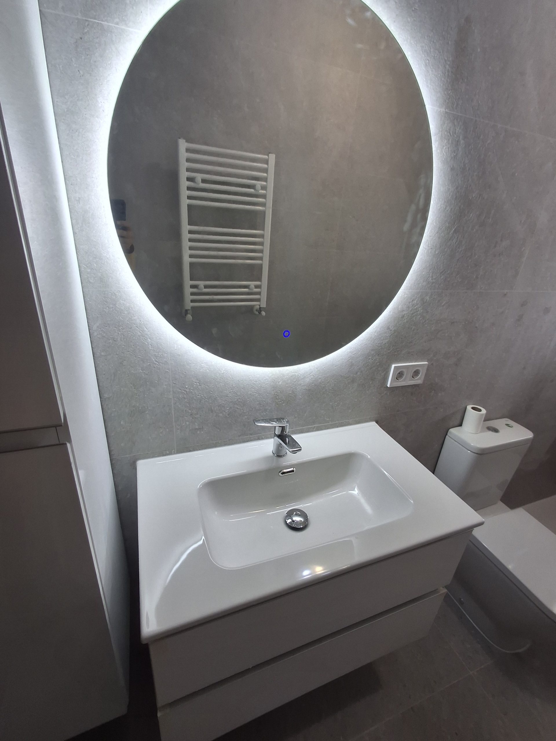 Lavabo y espejo retroiluminado en baño reformado en Carabanchel