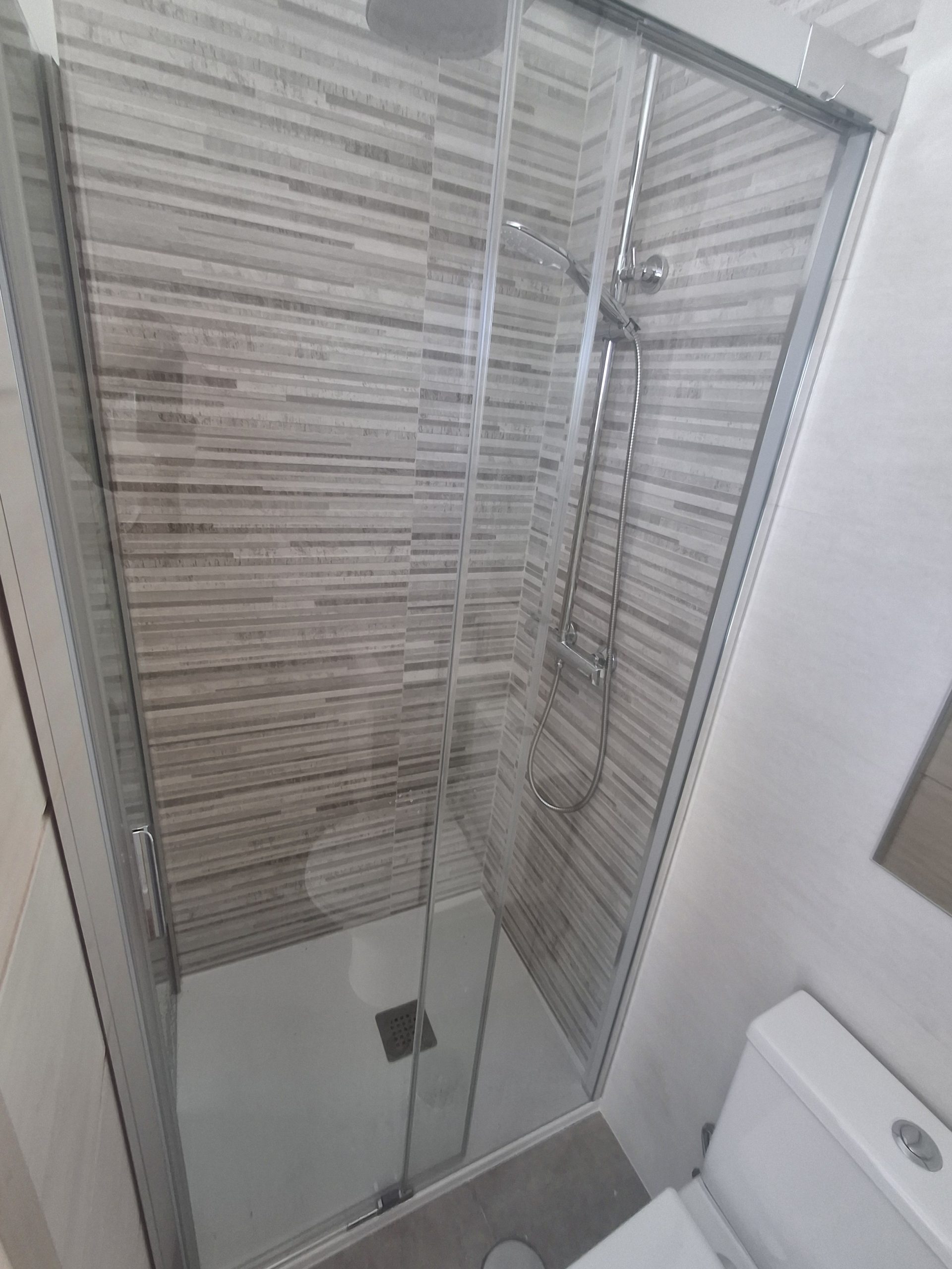 Detalle de ducha con mampara en baño reformado en Loeches